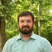 Greg Trotter standing among trees. 