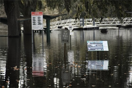 Boat ramp, picknic tables and signs under water due to flooding.