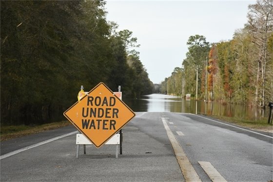 Road under water sign on a road that is partially covered in water.